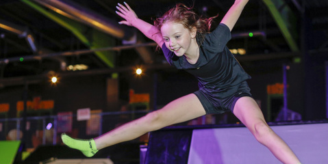 Girl doing a star jump off a trampoline at Flipout